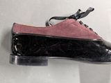 pink and black shoes on a white surface with a black shoelace