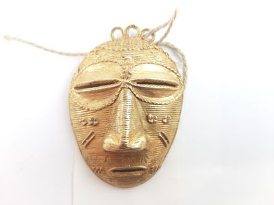 an image of a gold mask hanging on a white wall