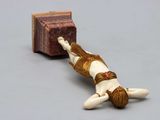 a figurine of a woman laying on the ground next to a book
