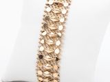 a close up of a gold bracelet on a pillow