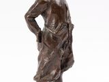 bronze statue of a boy standing on a rock with his hands on his hips