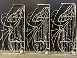 three metal racks with wires attached to them against a black wall
