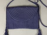 purple purse with tassels hanging from it on a wall