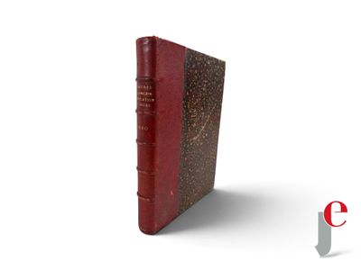 an old book with a red cover sitting on top of a white surface