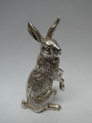 une image représentant une figurine de lapin en argent assise sur ses pattes arrière