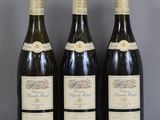 Trois bouteilles de vin sont alignées sur une table en verre