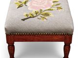 an upholstered foot stool with a needled rose on it