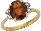 gros plan d'une bague en or avec une pierre rouge et des diamants