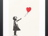 une photo en noir et blanc d'une petite fille tenant un ballon rouge