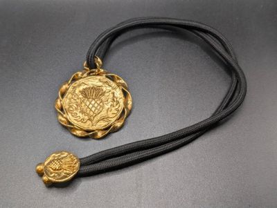 a close up of a necklace with a gold medallion on it