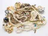 un tas de perles et d'autres bijoux posés sur une surface blanche