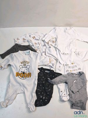 many baby clothes laid out on a white surface