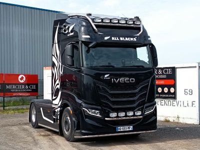 un gros semi-remorque garé devant un immeuble