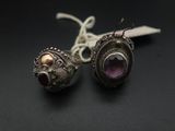 paire de boucles d'oreilles en argent ornées d'améthyste et de grenats sur un fond noir