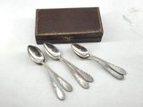 three silver spoons and a box on a white surface