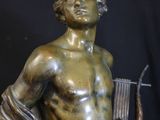 bronze statue of a man holding a harp and a bow