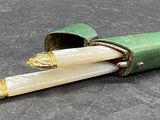 un étui vert contenant deux bougies blanches