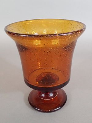 un vase en verre brun avec un socle brun posé sur une table