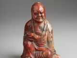 une petite statuette rouge et blanche représentant un Bouddha assis