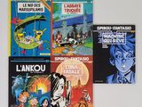 Plusieurs livres sont alignés sur une surface blanche devant un mur blanc.