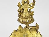 a gold statue of a woman holding a bird on a rock