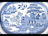 an image of a blue and white plate with a bird flying over it