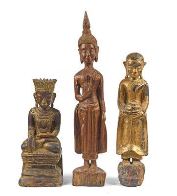 trois statues de Bouddha en bois et un Bouddha assis sur un rocher