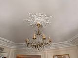 un lustre au milieu d'une pièce dont les murs sont ornés de tableaux