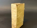 an old book sitting on top of a table on a black surface