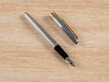 a pen and a ballpoint pen on a wooden table