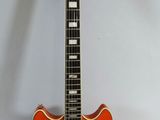 an orange electric guitar sitting on top of a white surface