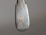 a silver spoon with a silver handle hanging from it