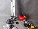 un appareil photo, un trépied, un objectif, un étui pour appareil photo et d'autres objets disposés sur une table