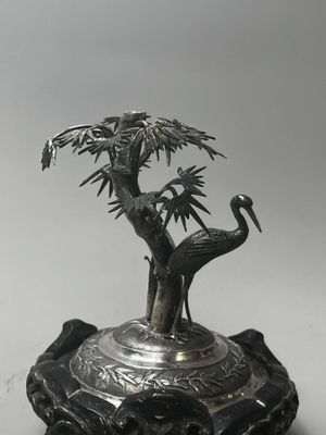 figurine plaquée argent représentant deux oiseaux et un arbre, posée sur un socle