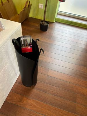 a black trash can sitting on the floor next to a window