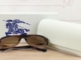 sunglasses in a white box and a pair of brown sunglasses on a wooden table