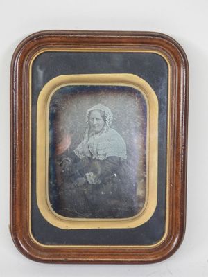 an old photo of a woman sitting in front of a white wall