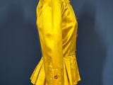 yellow jacket on a mannequin stand against a blue wall