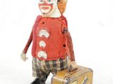 un petit clown en peluche avec une valise, posé sur une surface blanche