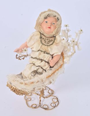 une poupée assise sur une chaise ornée de fleurs
