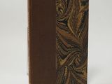 an old book with a brown cover sitting on top of a white surface