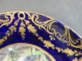 a blue and gold plate with a picture of a woman on it