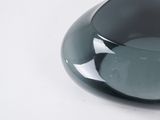 a black glass bowl with a hole in it on a white surface