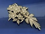 une image représentant une broche en or ornée de fleurs et de feuilles