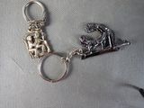 a silver keychain with a picture of a woman on a bench