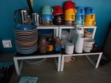 many plates and cups on a shelf in the kitchen