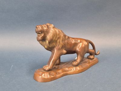 statue en bronze représentant un lion perché sur un rocher, sur fond bleu