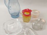 a glass pitcher, a bowl, and other glass items on a table
