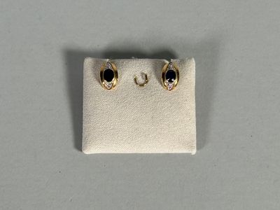 a pair of gold earrings with black stones on a white surface