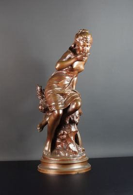statue en bronze représentant une femme tenant un oiseau, posée sur une table noire